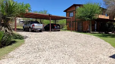 a driveway with cars parked in front of a house at Cabañas Lo de Alberto in Santa Rosa de Calamuchita