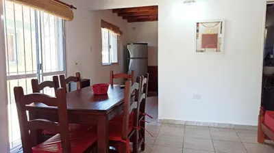 a kitchen with a wooden table and a refrigerator at Cabañas Lo de Alberto in Santa Rosa de Calamuchita