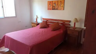 a bedroom with a bed with a pink bedspread at Cabañas Lo de Alberto in Santa Rosa de Calamuchita