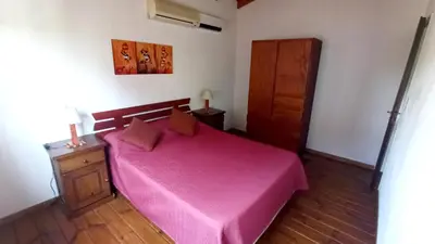 a bedroom with a pink bed and a wooden floor at Cabañas Lo de Alberto in Santa Rosa de Calamuchita