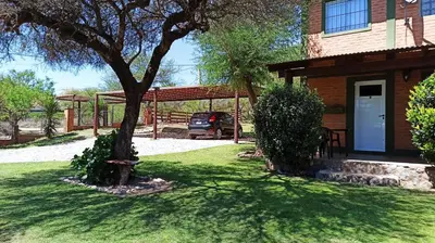 a house with a tree in the yard at Cabañas Lo de Alberto in Santa Rosa de Calamuchita