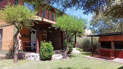 a brick house with trees in the yard at Cabañas Lo de Alberto in Santa Rosa de Calamuchita