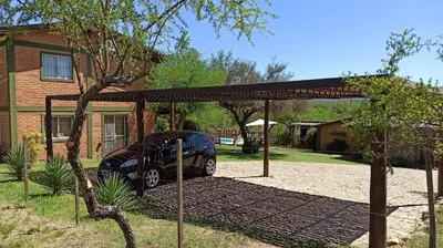 a car parked under a pavilion in front of a house at Cabañas Lo de Alberto in Santa Rosa de Calamuchita