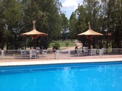 a pool with umbrellas and tables and chairs next to at CABAÑAS VIEJO VIVERO in Mina Clavero