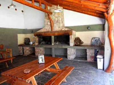a room with a wooden table and a stone fireplace at CABAÑAS VIEJO VIVERO in Mina Clavero