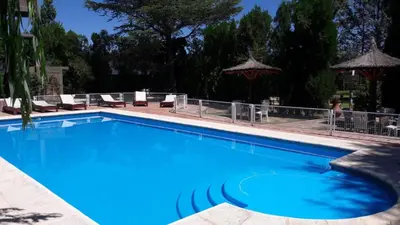 a large blue swimming pool with chairs and umbrellas at CABAÑAS VIEJO VIVERO in Mina Clavero