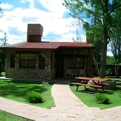 a house with a picnic table in front of it at CABAÑAS VIEJO VIVERO in Mina Clavero