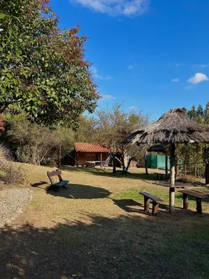 a park with two benches and a grass umbrella at Barranca Del Indio in Merlo