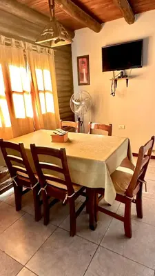 a dining room table with chairs and a television at Cabañas El Trigal in Nono
