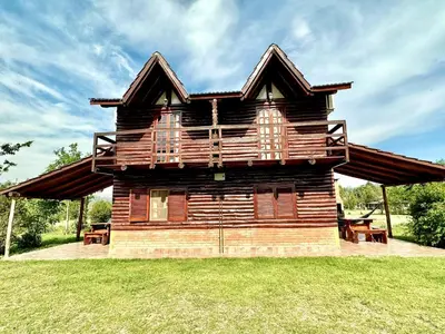 a log cabin with a deck on the grass at Cabañas El Trigal in Nono
