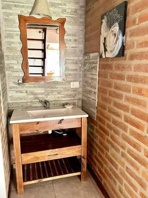 a bathroom with a sink and a brick wall at Cabañas El Trigal in Nono