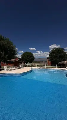 a large blue swimming pool with chairs and trees at Cabañas El Trigal in Nono