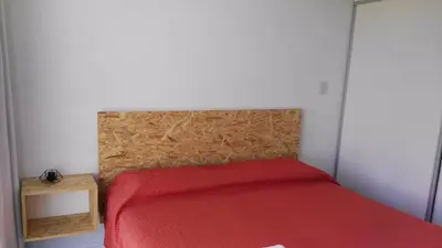 a bedroom with a red bed with a wooden headboard at Apart FJL in Río Cuarto