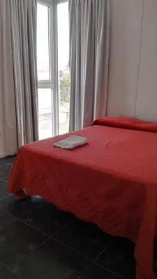 a bed with a red blanket and a window at Apart FJL in Río Cuarto