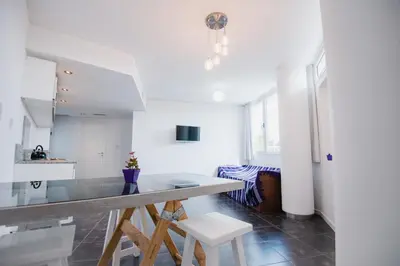 a kitchen with white cabinets and a table and chairs at Apart FJL in Río Cuarto