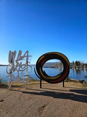 a metal sign sitting next to a body of water at Depto VCP Rental in Villa Carlos Paz