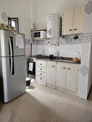 a kitchen with a stainless steel refrigerator and white cabinets at Depto VCP Rental in Villa Carlos Paz
