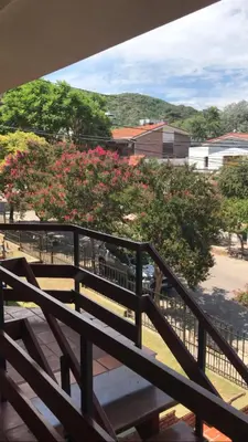 a balcony with a wooden railing and pink flowers at Depto VCP Rental in Villa Carlos Paz