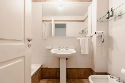 a white bathroom with a sink and a mirror at Departamentos Lugar in Cordoba