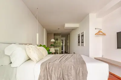 a white bedroom with a large bed with white pillows at Departamentos Lugar in Cordoba