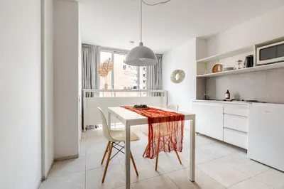 a white kitchen with a white table and chairs at Departamentos Lugar in Cordoba