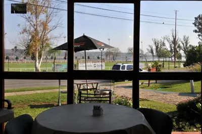 a table with an umbrella viewed through a window at Madeo Hotel & Spa in Villa Carlos Paz