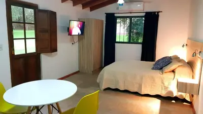 a bedroom with a bed and a table and a tv at Cabañas Landhaus in Villa General Belgrano