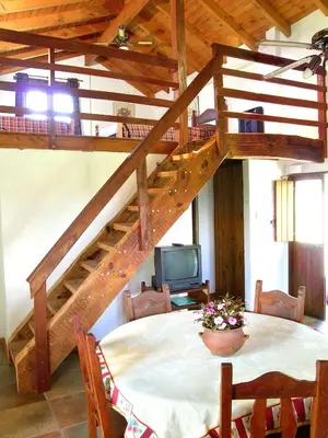 a dining room with a table and a spiral staircase at Cabañas Landhaus in Villa General Belgrano
