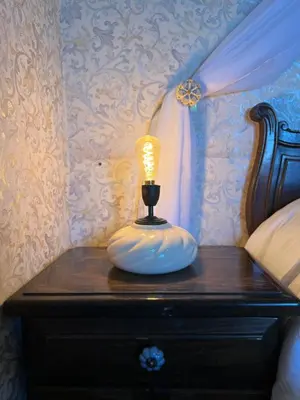 a lamp sitting on a table next to a bed at Juliette Posada Boutique Ex Posada La Villa in Villa Carlos Paz