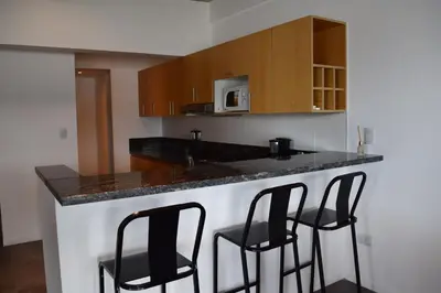 a kitchen with a counter and three black bar stools at Puerto del Águila Departamentos sobre el Lago - The View Luxury Aparts in Potrero de Garay