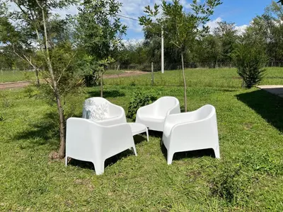 a group of white chairs sitting in the grass at El Retiro - Casa de campo en Los Reartes in Los Reartes