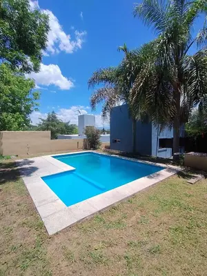 a swimming pool in a yard with a palm tree at Casa en Barrio Costa Azul in Villa Carlos Paz