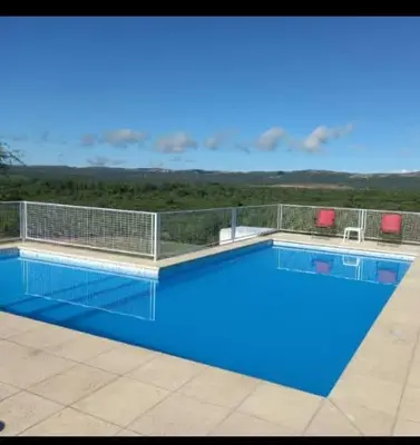a swimming pool with blue water and two red chairs at La bendicion in Villa Cura Brochero