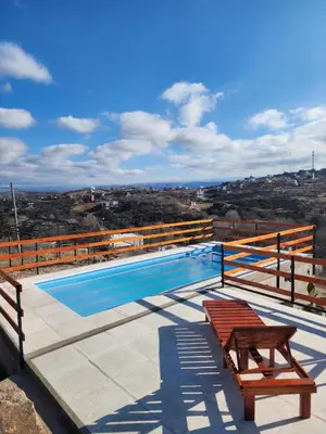 a swimming pool with two benches on a roof at Cabañas Dulce Atardecer in Villa Carlos Paz