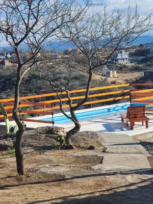two trees and a bench next to a fence at Cabañas Dulce Atardecer in Villa Carlos Paz