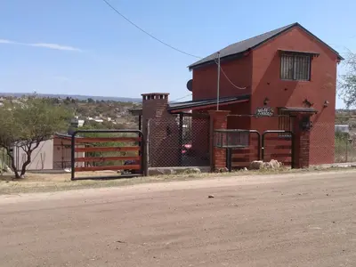 a red brick building with a gate on the side of a road at Cabañas Dulce Atardecer in Villa Carlos Paz