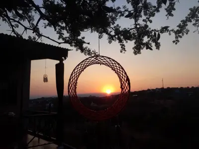 a wicker basket hanging from a tree with the sunset in the background at Cabañas Dulce Atardecer in Villa Carlos Paz