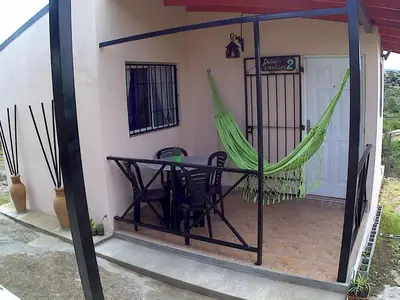 a patio with a hammock and a table and chairs at Cabañas Dulce Atardecer in Villa Carlos Paz