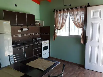 a kitchen with green walls and a table and a window at Cabañas Dulce Atardecer in Villa Carlos Paz