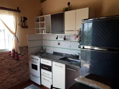 a kitchen with a stove and a refrigerator at Cabañas Dulce Atardecer in Villa Carlos Paz