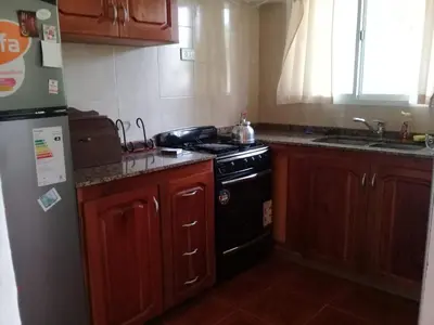 a kitchen with wooden cabinets and a black stove at La casita de Chany in Mina Clavero