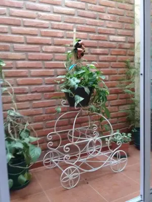 a plant holder in front of a brick wall at La casita de Chany in Mina Clavero