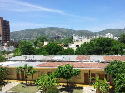 a building with trees and mountains in the background at 76 Arruabarrena in Villa Carlos Paz