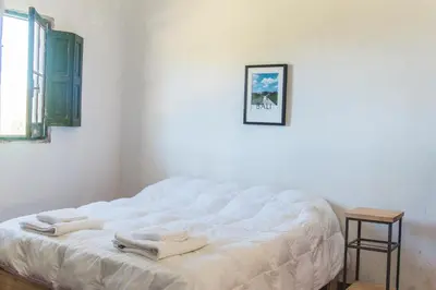 a white bed in a room with two towels on it at Posada Las Vertientes in Copina