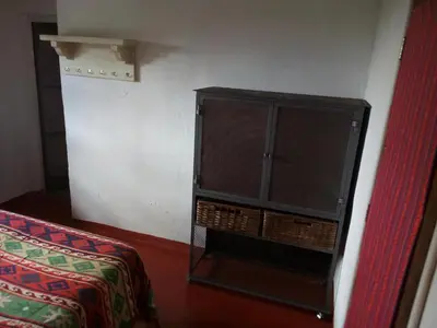 a black cabinet in a room with a bed at Posada Las Vertientes in Copina