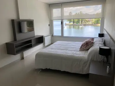 a bedroom with a bed and a tv and a large window at Casonas de la Bahia in Villa Carlos Paz
