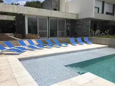a group of blue lounge chairs next to a swimming pool at Casonas de la Bahia in Villa Carlos Paz