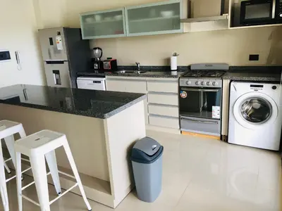 a kitchen with a counter and a washing machine at Casonas de la Bahia in Villa Carlos Paz
