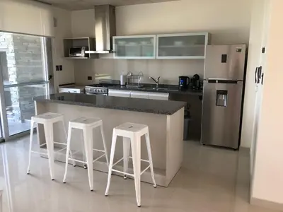 a kitchen with a counter with stools and a refrigerator at Casonas de la Bahia in Villa Carlos Paz