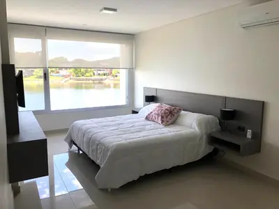 a bedroom with a bed and a large window at Casonas de la Bahia in Villa Carlos Paz